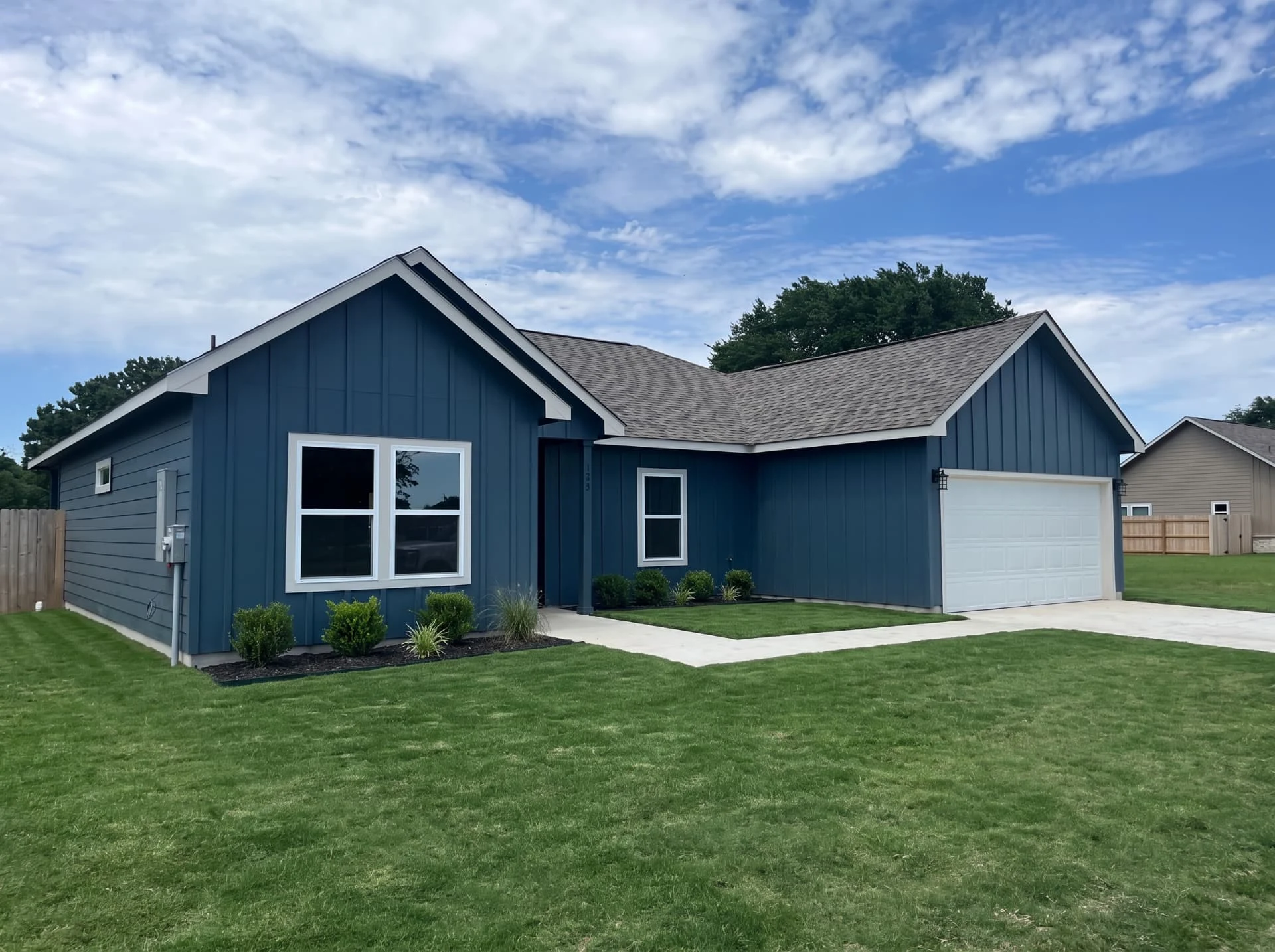 Blue board and batten new construction home with two-car garage and fresh lawn