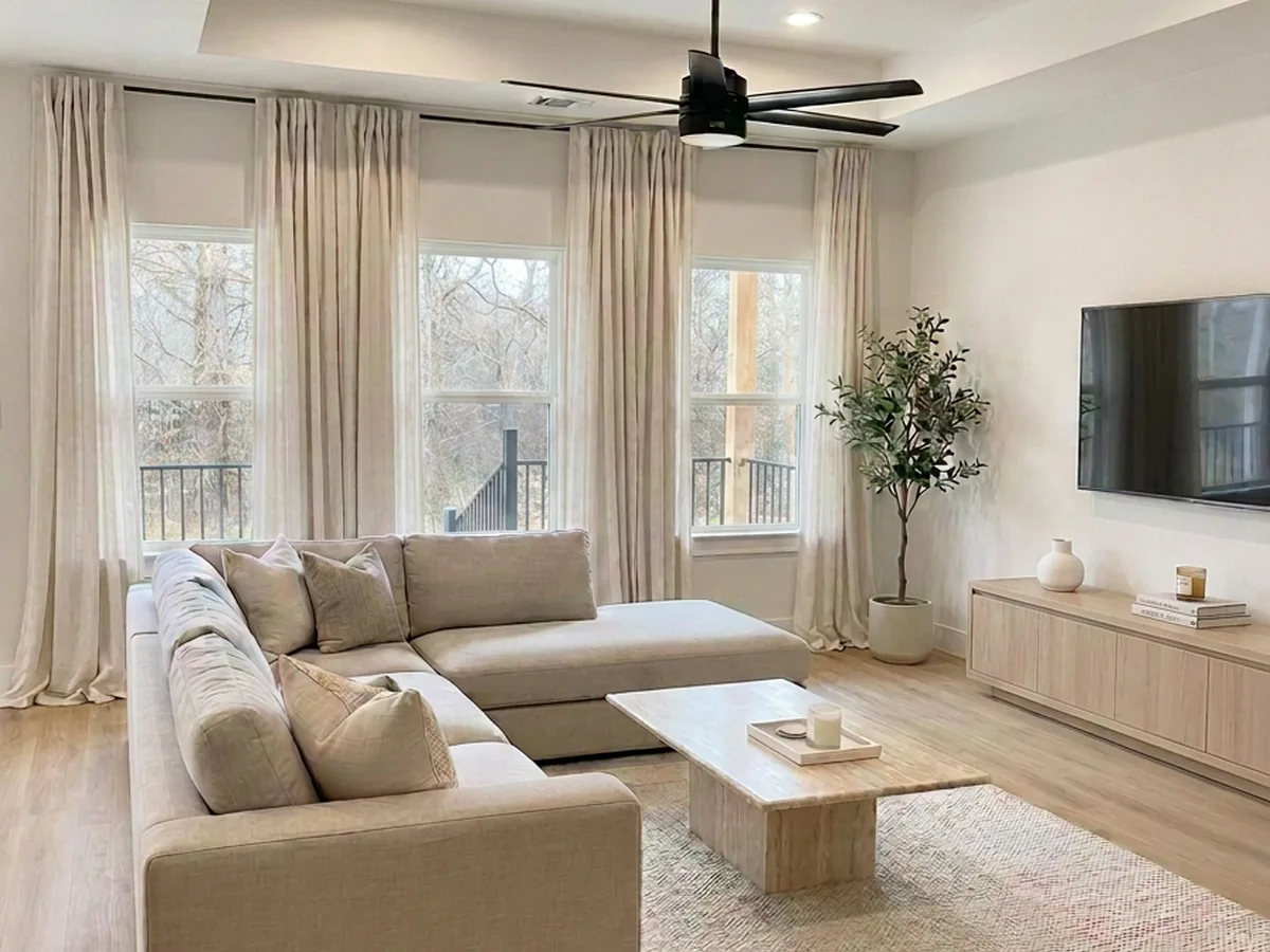 Living room with sectional sofa, tray ceiling and tall curtained windows